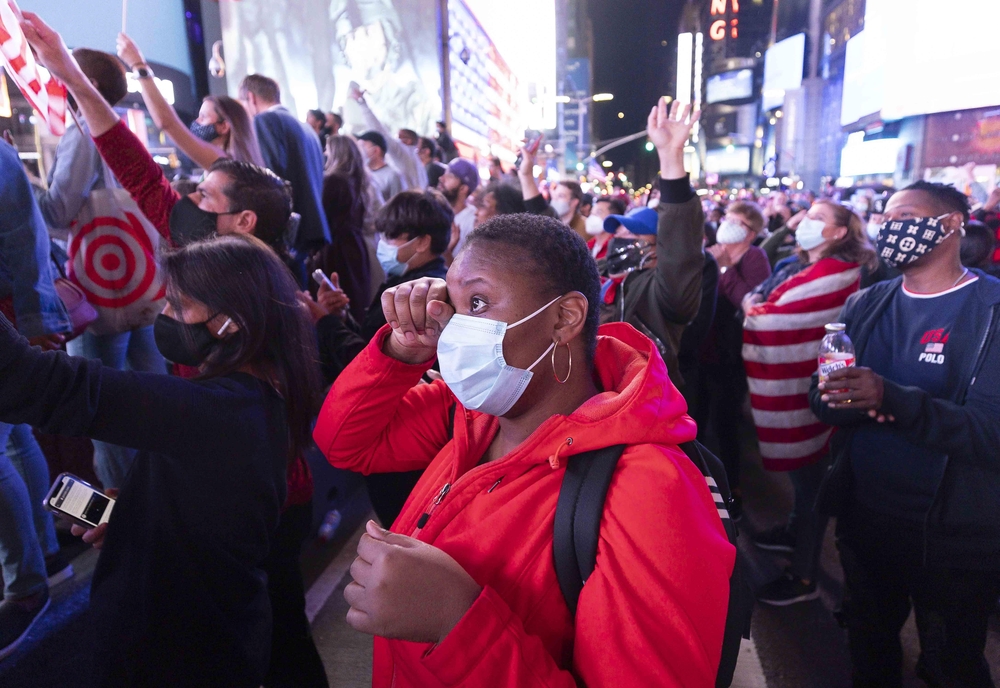 People watch US President-elect Joe Biden's speech in Time Square  / JUSTIN LANE