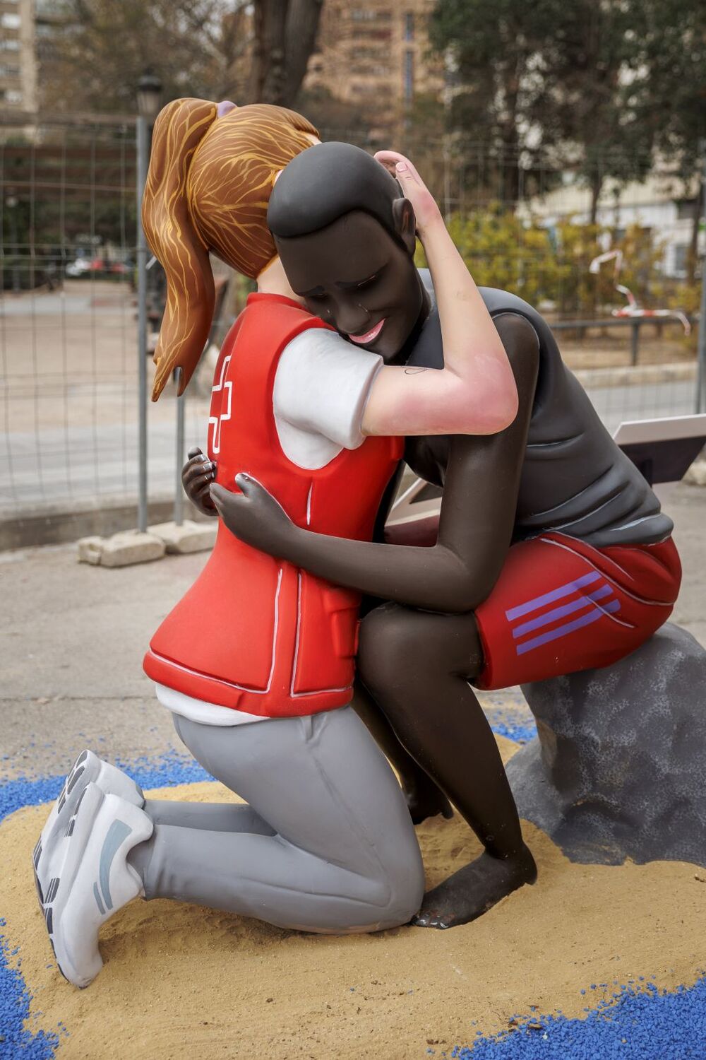 Un ninot simboliza el abrazo entre la voluntaria de Cruz Roja y el migrante Abdou  / BIEL ALIÑO